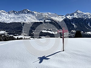 Hiking markings and orientation signs with signposts for navigating in the idyllic winter ambience of the Swiss Alps