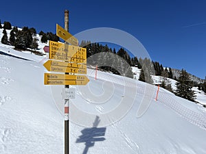 Hiking markings and orientation signs with signposts for navigating in the idyllic winter ambience of the Swiss Alps