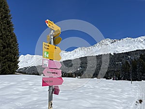 Hiking markings and orientation signs with signposts for navigating in the idyllic winter ambience of the Swiss Alps