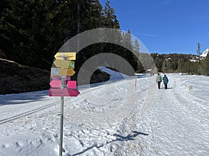 Hiking markings and orientation signs with signposts for navigating in the idyllic winter ambience of the Swiss Alps