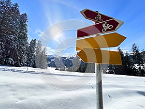 Hiking markings and orientation signs with signposts for navigating in the idyllic winter ambience of the Swiss Alps