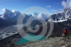 Hiking in Nepal Himalayas, Male tourist on Gokyo Ri with view of Gokyo lake, Gokyo village, Ngozumba glacier and mountain