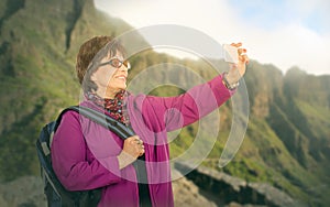 Hiking old woman photographing mountains