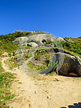 Hiking path to Gravata beach, a rock with `Take your trash` written on it - Florianopolis, Brazil