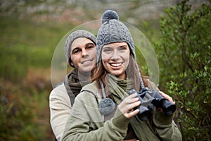 Hiking portrait, binocular and couple smile for nature getaway, weekend break and camping retreat in eco forest