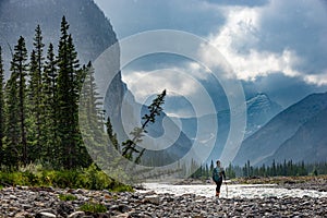 Hiking in the rain Woman Hiker crosses the Ghost River Trans Alta trail with Mt Aylmer in the background