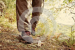 Hiking shoes with red laces and legs wearing long brown trousers