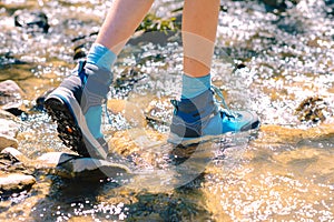 Hiking shoes - sole of trekking boots and legs in a mountain stream