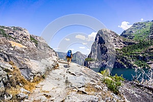 Hiking on the shoreline of Hetch Hetchy reservoir in Yosemite National Park, Sierra Nevada mountains, California; the reservoir is