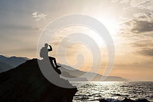 Hiking silhouette backpacker, man looking at ocean