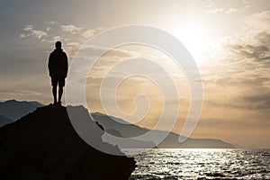 Hiking silhouette backpacker, man looking at ocean photo