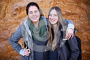 Hiking is their shared passion. Portrait of two attractive young female hikers standing by a rockface.