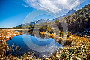 Hiking to mountain lake in National Park High Tatra in autumn and sunny day. Dramatic overcast sky. Zelene pleso, Slovakia, Europe