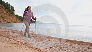 Hiking tourism adventure. Hiker girl lady tourist with backpack walking near lake. Backpacker hiker woman enjoying