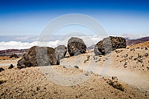 Hiking trail above the clouds descending the El Teide Volcano with large volcanic boulders. Tenerife, Canary Islands