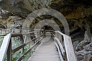 Hiking trail boardwalk under rocky overhang