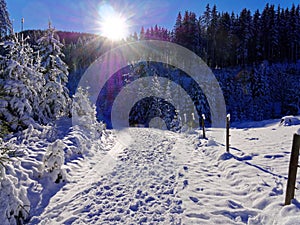 Hiking trail in deep snow-covered mountainous region by dazzling sun