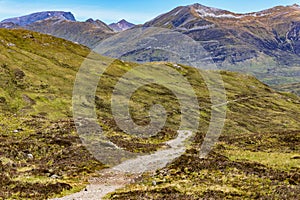 A hiking trail eading towards spectacular mountains with traces of summer snow (Ben Nevis and range, Scotland