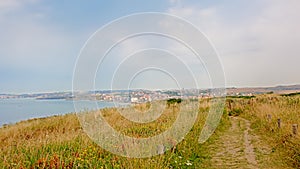 Hiking trail in a field on the ciffs on the French Northe sea coast, with the city of Wiemereux in the background