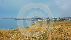 Hiking trail in a field on the ciffs on the French North sea coast, with the city of Wiemereux in the background photo