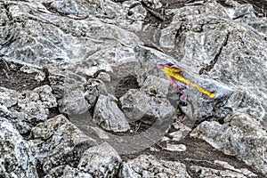 Hiking trail. A grey rocky road up the mountain with a yellow arrow drawn to indicate the way. Restrained colors of nature