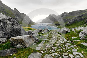 Hiking trail leading to a beautiful bay surrounded by mountains and a small village near Bunes Beach and Vinstad on Lofoten Island