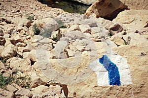 Hiking trail marker painted on a stone in rocky desert area