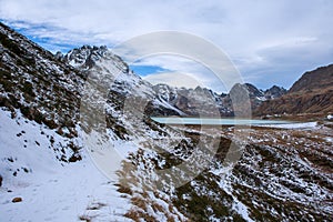 Hiking trail in the mountains with snow, silvretta in austria with a view of the dam