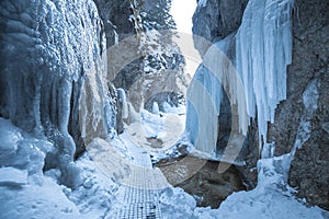 Hiking trail through a narrow gorge covered with snow and ice.