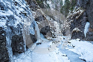 Turistická stezka úzkou soutěskou pokrytou sněhem a ledem.