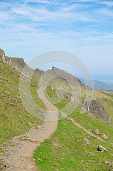 Hiking trail in Scottish terrain with green field and cliff. Adventurous trail for outdoor activity on the hill.