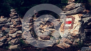Hiking trail sign mark painted on a rock in stack of zen stones. Path leading trough the beautiful Bohemian Forest National Park.