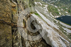 Hiking trail on steep slope guarded by chain over Spisske plesa tarns in High Tatras mountains