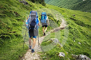 Hiking trail in Svaneti region, Georgia. Two hikers men walk on trek in mountain. Tourists with backpacks hike in highlands