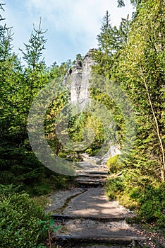 Hiking trail with trees around and rock towers in Teplicke skaly in Czech republic