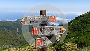 Hiking trail wooden signs with destinations and distances on a pole