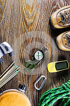 Hiking or travel equipment with boots, compass, binoculars, matches on wooden background. Active lifestyle concept