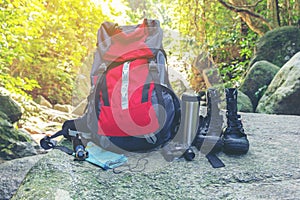 Hiking travel gear on glasses. Items include hiking boots, cup, map,binoculars. Flat lay of outdoor travel equipment items for