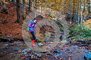Hiking woman with backpack crosses the stream
