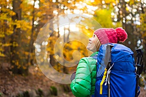 Hiking woman with backpack looking at inspirational autumn golden woods