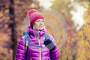 Hiking woman with backpack looking at inspirational autumn golden forest