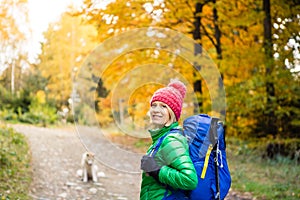 Hiking woman with backpack looking at inspirational autumn golden woods