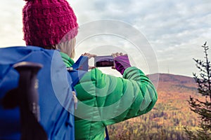 Hiking woman with backpack taking photo with smartphone