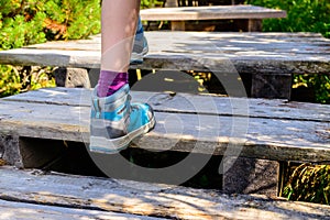 Hiking woman with boots on wooden trail, outdoors activity