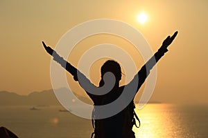 Hiking woman open arms to sunrise