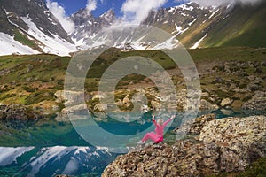 Hiking woman in red clothes sitting at beautiful turquoise lake in mountains.