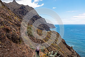 Hiking woman with scenic view of coastline of Anaga mountain range on Tenerife, Canary Islands, Spain. View on Cabezo el Tablero photo