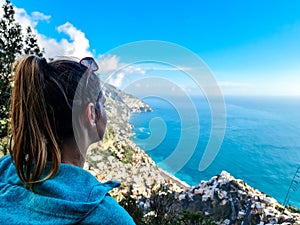 Hiking woman with scenic view from Monte Comune on clouds covering the coastal town Positano at the Amalfi Coast, Campania, Italy.