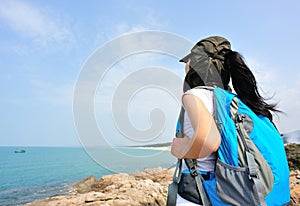 Hiking woman stand seaside rock