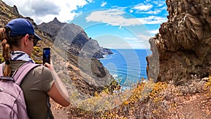 Hiking woman taking picture of scenic view of coastline of Anaga mountain range on Tenerife, Canary Islands, Spain, Europe photo